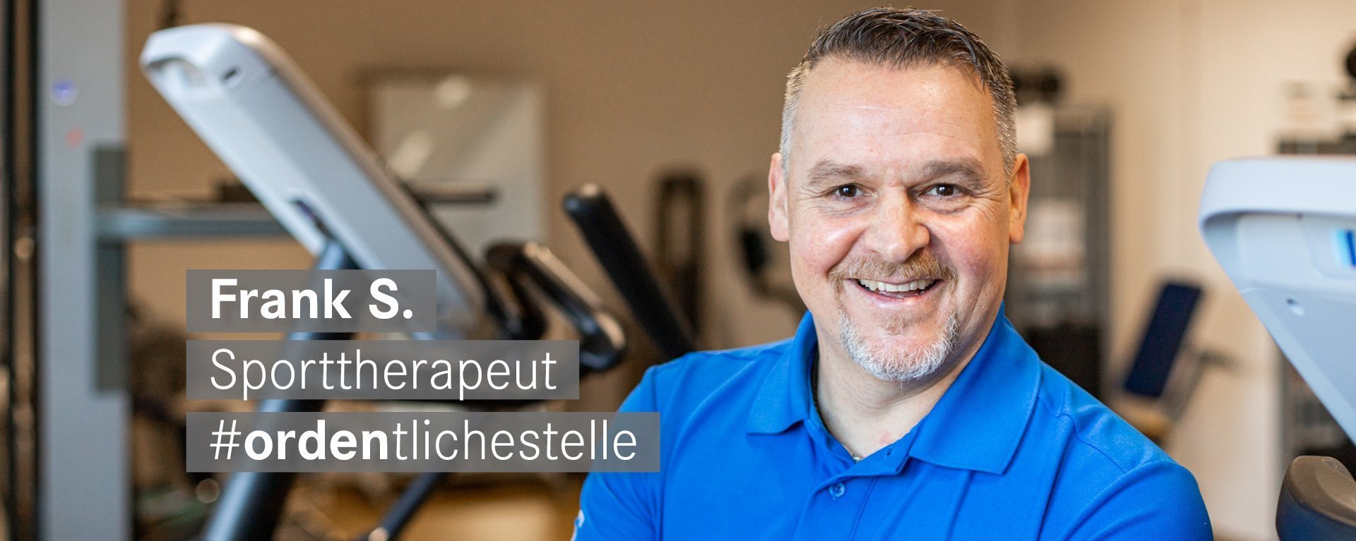 Sporttherapeut mit wenig Bart laechelt freundlich in die Kamera