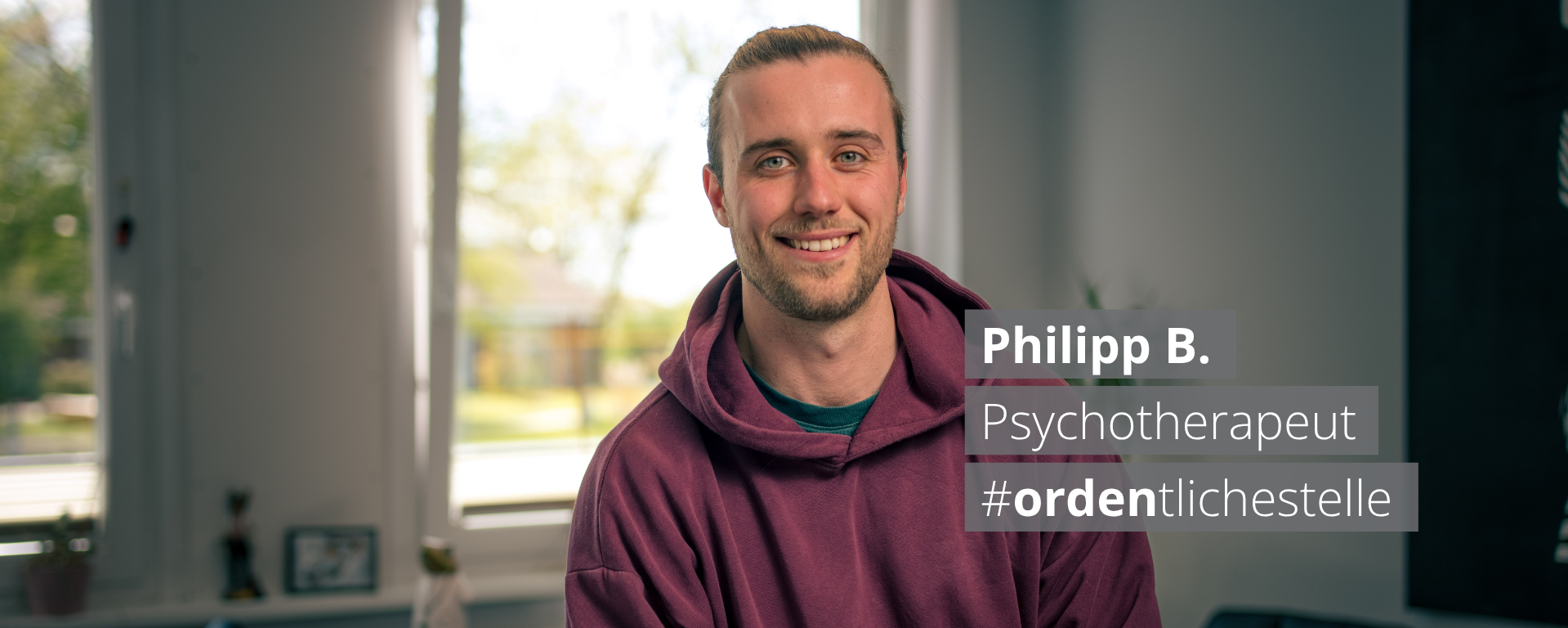 Porträt von Philipp B., einem lächelnden Psychotherapeuten in einem lila Hoodie. Ein Textoverlay nennt seinen Namen, Beruf und den Hashtag #ordentlichestelle vor dem Hintergrund eines hellen Büros.