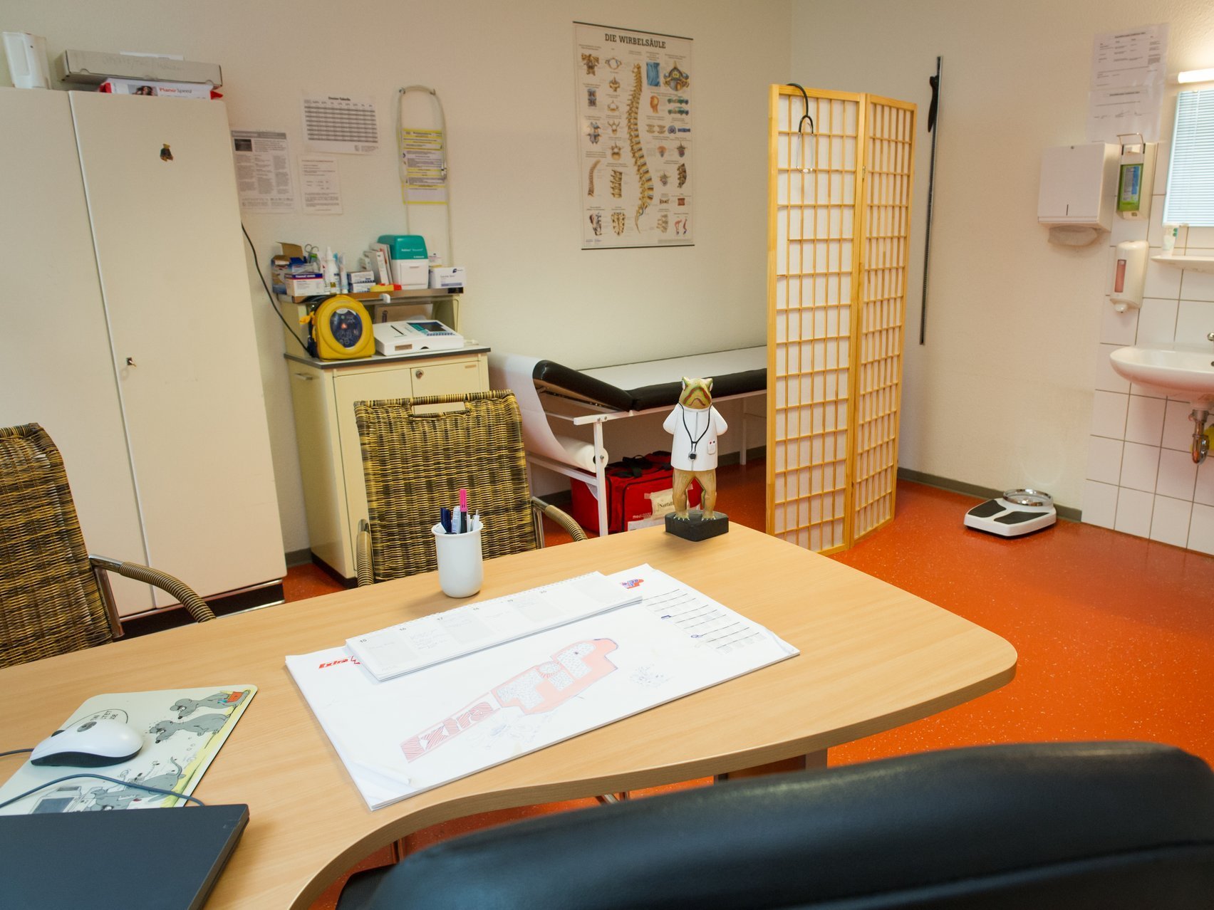 Arztzimmer mit Schreibtisch und Untersuchungsliege und Waschbecken